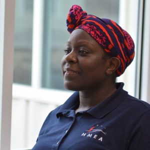 Woman of color wearing a red head wrap and an blue ϲ polo shirt